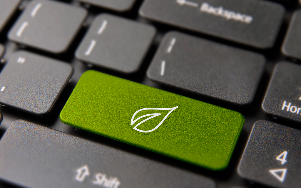 Green energy button on laptop keyboard with leaf icon, symbolizing environmental awareness and sustainability